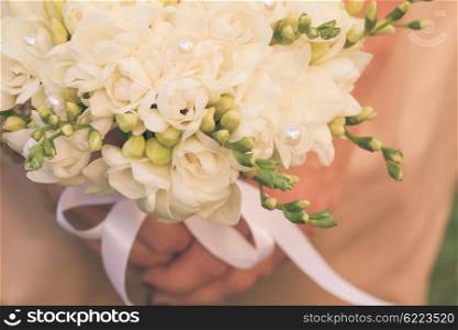 Wedding bouquet with white freesias closeup in bride&amp;#39;s hands