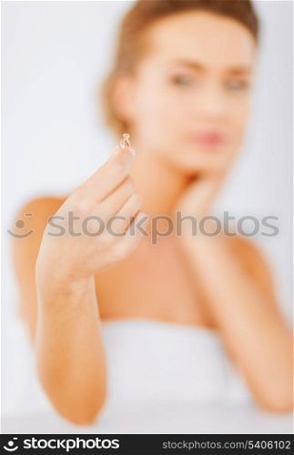 wedding, bridal, jewellery and luxury concept - beautiful woman looking at wedding ring and thinking