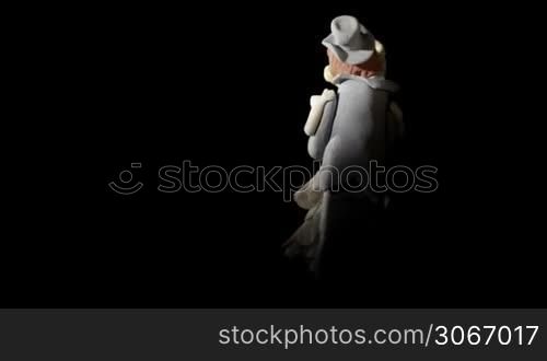 Wedding cake figurines are rotating and kissing on black background.