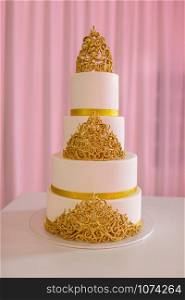 wedding cake with gold. Wedding cake, on white table. 3-tiers covered in ivory fondant sprayed with pearl spray and yellow roses made of sugar paste.. Wedding cake, on white table. 3-tiers covered in ivory fondant sprayed with pearl spray and gold roses made of sugar paste. wedding cake with gold