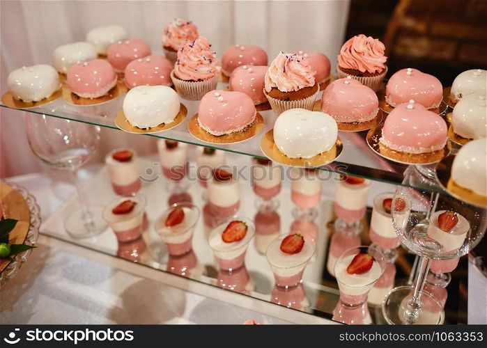 Wedding candy bar with pink and white deserts. Strawberry cupcakes, jelly and modern desserts. Wedding candy bar with pink and white deserts. Strawberry cupcakes, jelly and modern desserts.