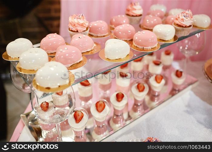 Wedding candy bar with pink and white deserts. Strawberry cupcakes, jelly and modern desserts. Wedding candy bar with pink and white deserts. Strawberry cupcakes, jelly and modern desserts.