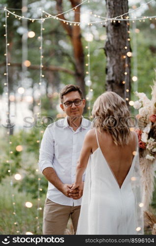 wedding ceremony of the marriage of a guy and a girl against the backdrop of an arch on a forest path