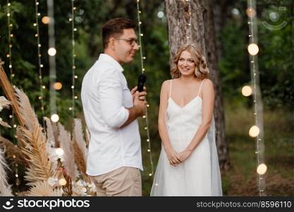 wedding ceremony of the marriage of a guy and a girl against the backdrop of an arch on a forest path