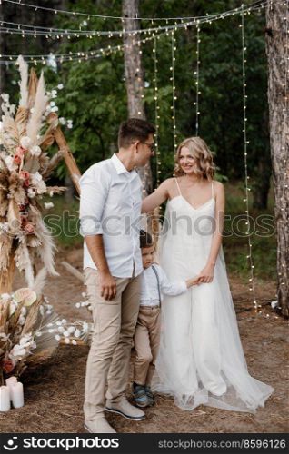 wedding ceremony of the marriage of a guy and a girl against the backdrop of an arch on a forest path