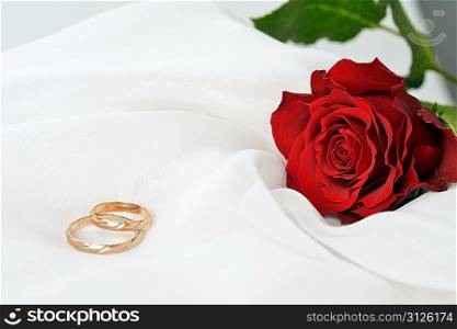 Wedding concept with rose and rings on white silk