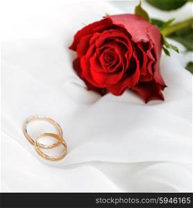 Wedding concept with rose and rings on white silk