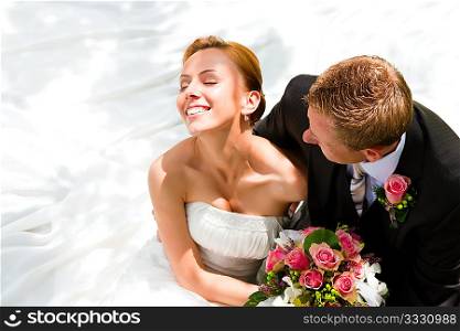 wedding couple hugging, the bride holding a bouquet of flowers in her hand, the groom embracing her