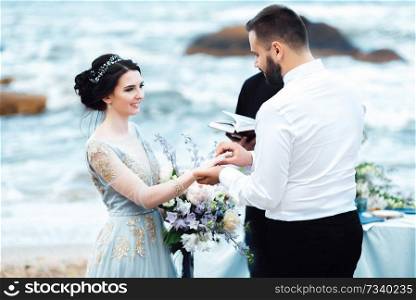 wedding couple on the ocean with a priest