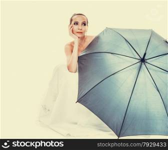 Wedding day at a raining day. Full length romantic bride white gown holding blue umbrella filtered photo