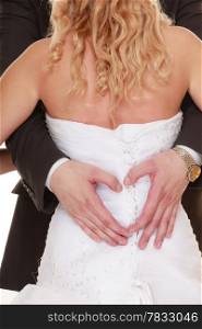 Wedding day. Closeup of male hands on back of bride in white dress. Man groom showing making heart shape love symbol. Studio shot.
