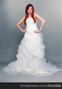 Wedding day. Portrait of happy beautiful blue eyed red haired bride long white dress in full length studio shot on gray background