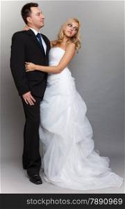 Wedding day. Portrait of happy married couple blonde bride and groom in full length studio shot on gray background