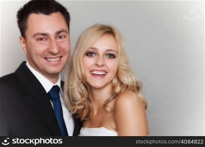Wedding day. Portrait of happy married couple blonde bride and groom studio shot on gray background