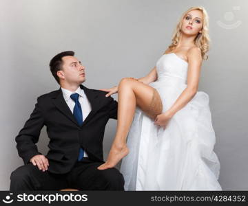 Wedding day. Portrait of happy married couple sexy blonde bride and groom in full length studio shot on gray background