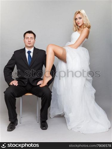 Wedding day. Portrait of happy married couple sexy blonde bride and groom in full length studio shot on gray background