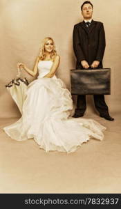 Wedding day. Portrait of married retro couple blonde bride with umbrella and groom with suitcase. Full length studio shot sepia color, vintage photo