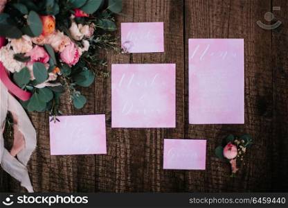 wedding decor with a rose and invitations, on a wooden background