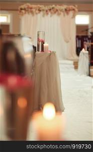 wedding decoration a candle and a vase with water on a white table. The vases with water and candles stand on the wedding table. wedding decoration a candle and a vase with water on a white table. Flasks with water and a floating candle
