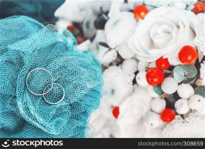 Wedding engagement rings on blurred background with white and red flowers. Shallow soft selective focus.. Wedding Engagement Rings Blurred Background
