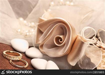 wedding favors and wedding ring on on colored background