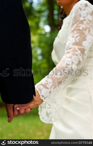 Wedding feelings. Couple holding hands. Natural green background.