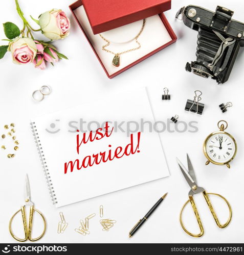 Wedding flat lay background with gift box, golden rings and rose flowers. Sample text just married