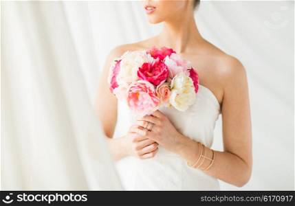 wedding, holidays, beauty, jewelry and luxury concept - close up of beautiful woman or bride with flower bouquet wearing golden ring and bracelet