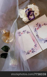 wedding invitation in a gray envelope on a table with green sprigs