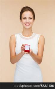 wedding, love, engagement and happiness concept - smiling woman in white dress holding red gift box with diamond ring over beige background