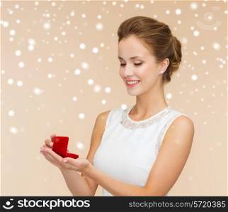wedding, love, engagement and happiness concept - smiling woman in white dress holding red gift box with diamond ring over beige background and snow