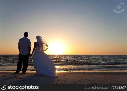 Wedding of a married couple, bride and groom, together at sunset on a beautiful tropical beach