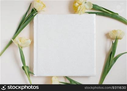 Wedding or family photo album, yellow tulips flowers on a light background; top view, flat lay, top view