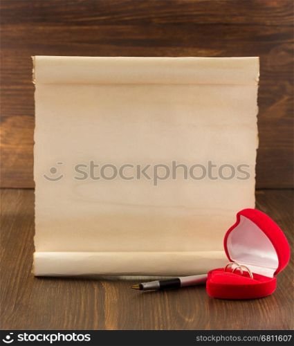 wedding ring and aged paper on wooden background