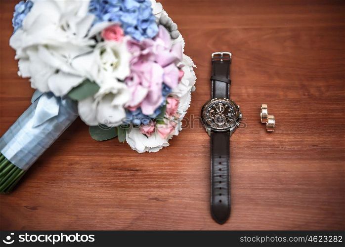 wedding ring and watch groom on the table with the wedding bouquet