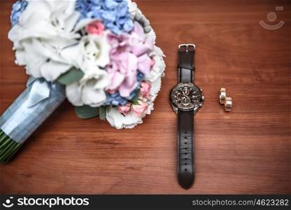 wedding ring and watch groom on the table with the wedding bouquet