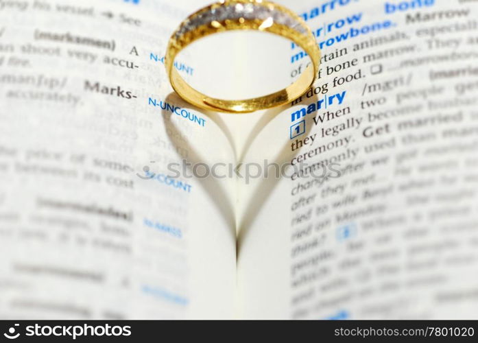 Wedding ring casting a heart onto a marry word