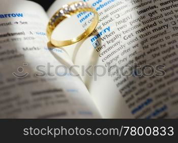 Wedding ring casting a heart onto a marry word with heart shape light