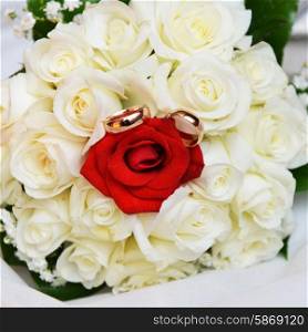 wedding rings and bride&rsquo;s bouquet of roses