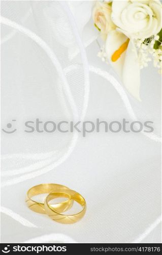wedding rings and flowers decorations over bridal veil