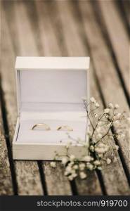 wedding rings in a box on the table. wedding rings in a box on the table. small flowers on a wooden table