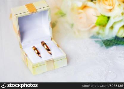 wedding rings in a box with bouquet from roses