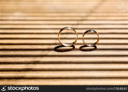 Wedding rings on a beautiful wooden texture surface closeup. two gold wedding rings are on the brown wood table