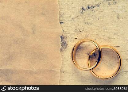 Wedding rings with paper piece on dirty canvas background