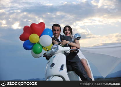 wedding sce of bride and groom just married couple on the beach ride white scooter and have fun