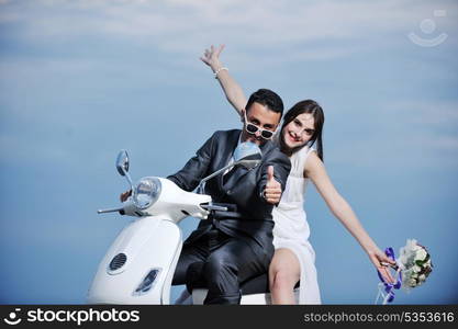 wedding sce of bride and groom just married couple on the beach ride white scooter and have fun