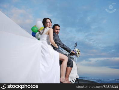 wedding sce of bride and groom just married couple on the beach ride white scooter and have fun