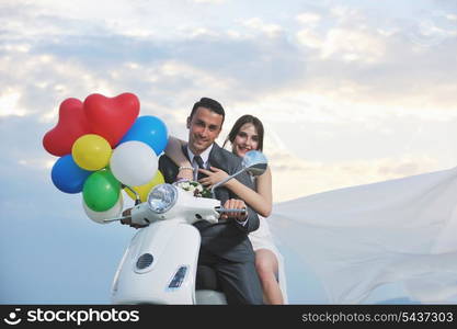 wedding sce of bride and groom just married couple on the beach ride white scooter and have fun