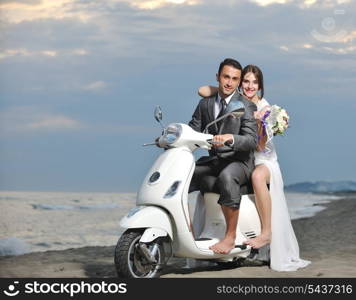 wedding sce of bride and groom just married couple on the beach ride white scooter and have fun