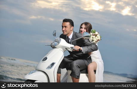 wedding sce of bride and groom just married couple on the beach ride white scooter and have fun